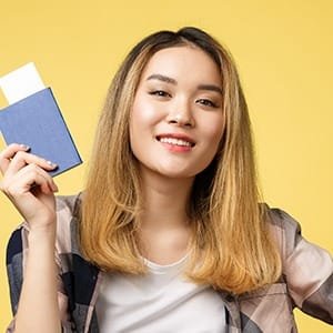 Smiling woman holding a blue passport, symbolizing the fast online application for a Schengen or UK ETA visa